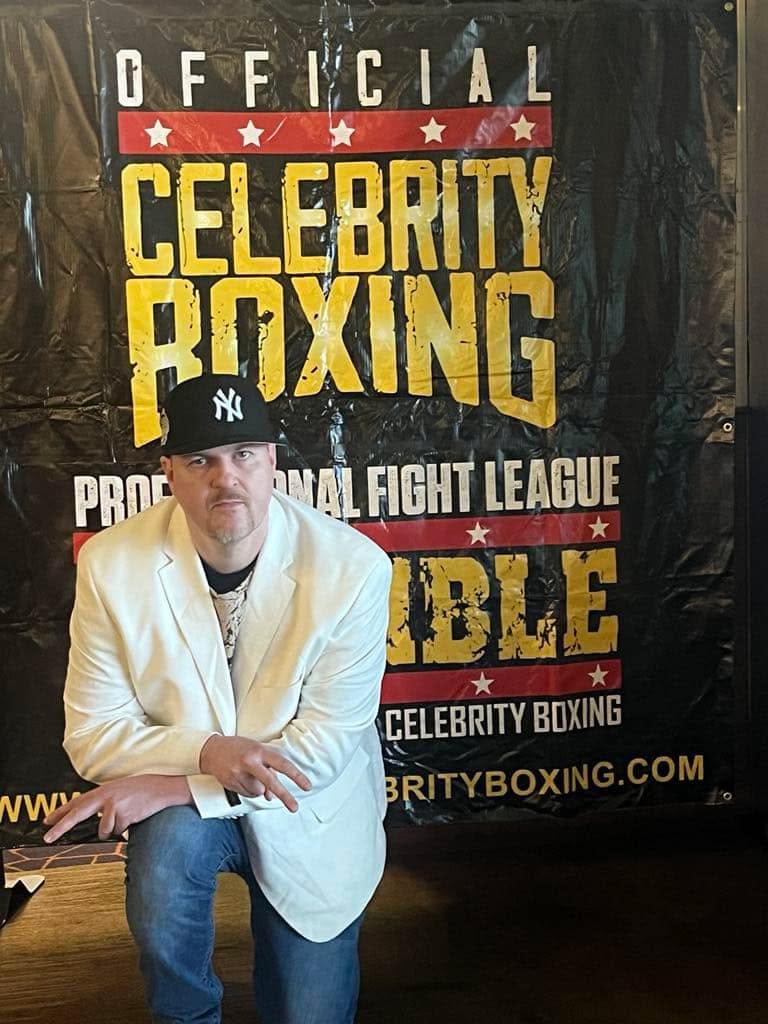 special needs rapper TU Savant posing in front of Official Celebrity Boxing banner in Philadelphia